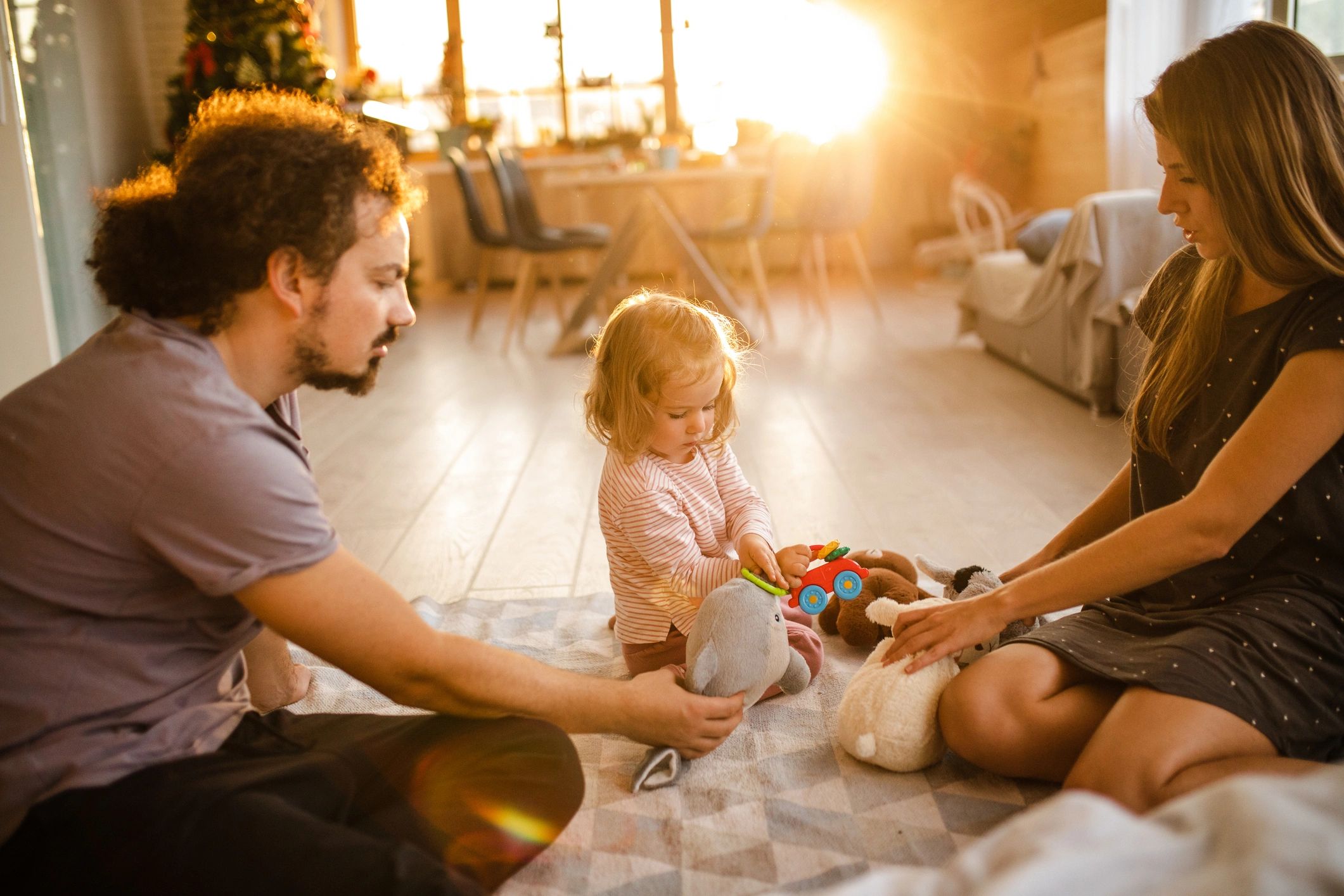 Parents playing with their toddler using soft toys