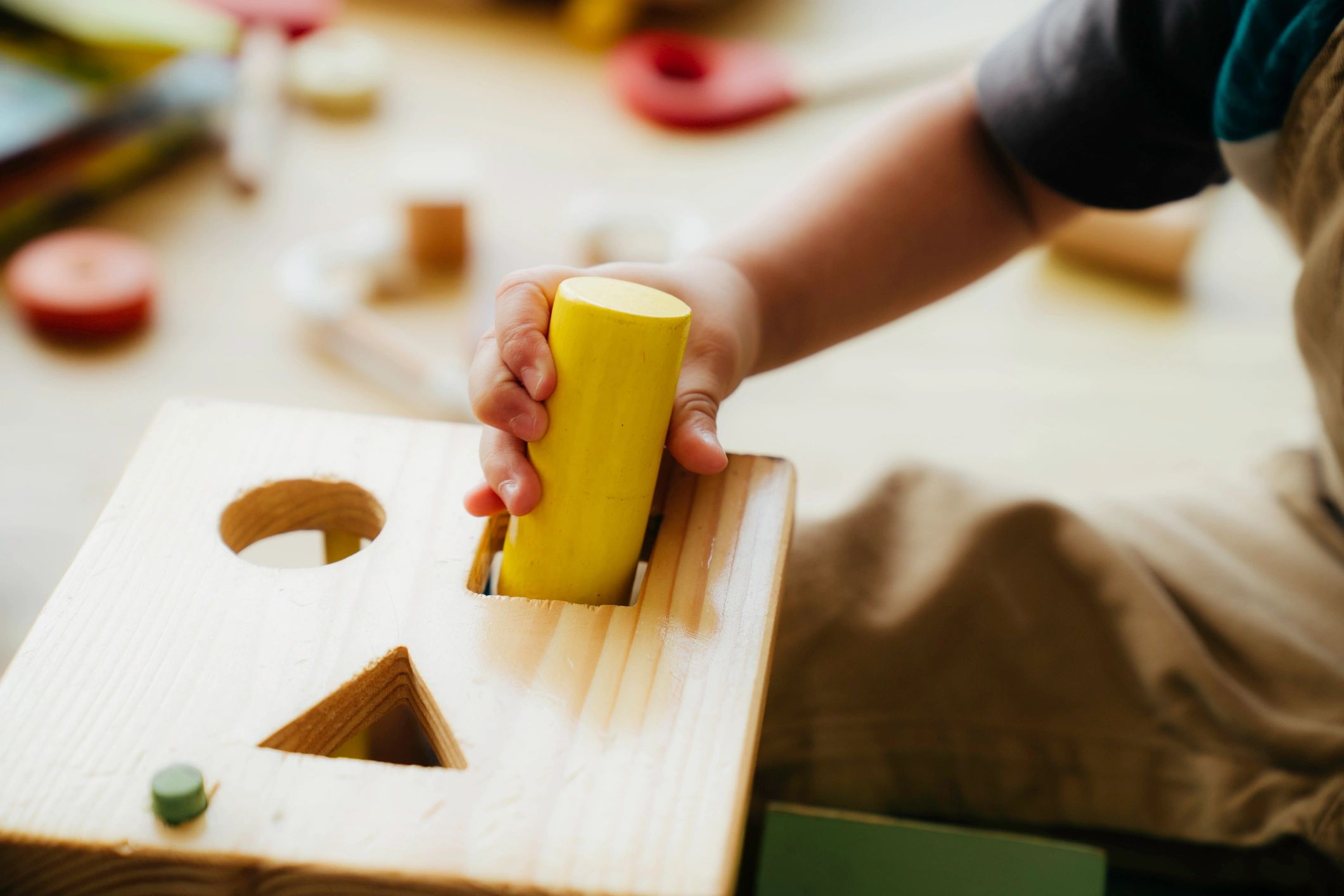 Baby hands exploring a wooden sensory toy